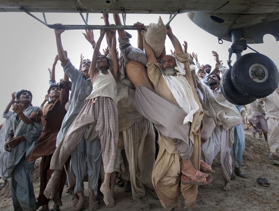 图片：遭受洪水侵袭的巴基斯坦灾民们试图抓住运输机