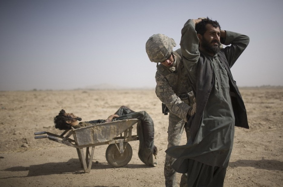 图片：美国士兵在搜查一名塔利班简易爆炸装置安装嫌疑犯的同伴